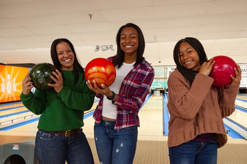women smiling with bowling balls