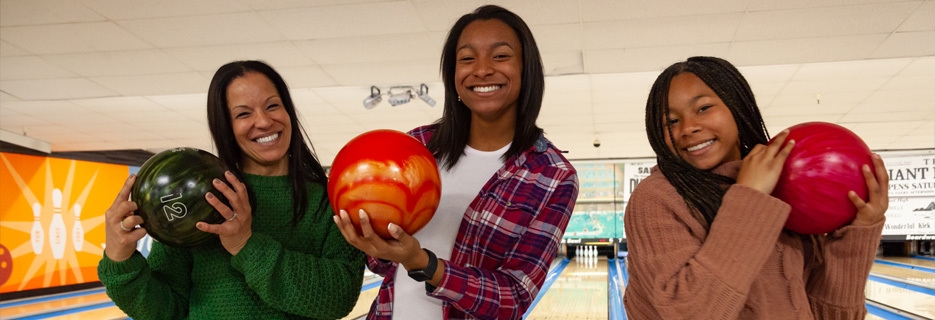 women smiling with bowling balls